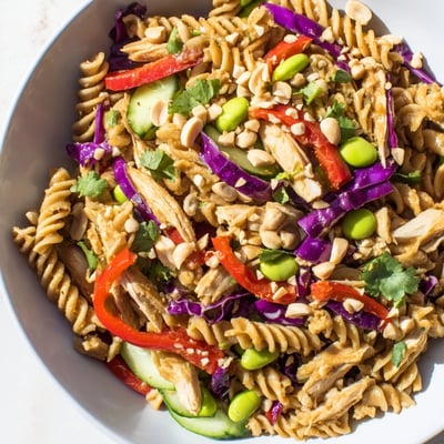 Grilled chicken and edamame top this protein packed Thai pasta salad in a bowl